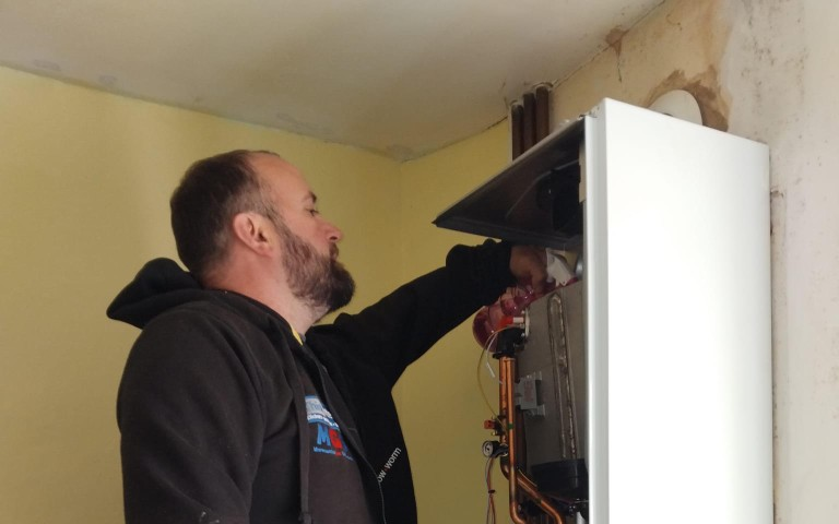 Gas engineer servicing a wall-mounted boiler during an annual service
